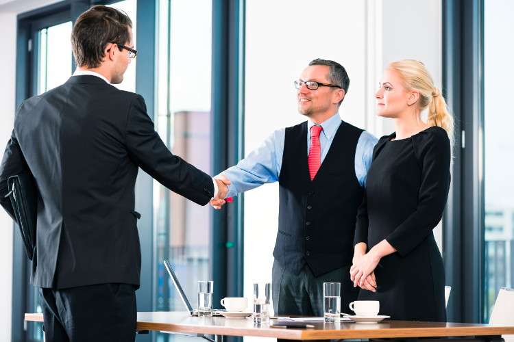 Job candidate shakes hands with employers
